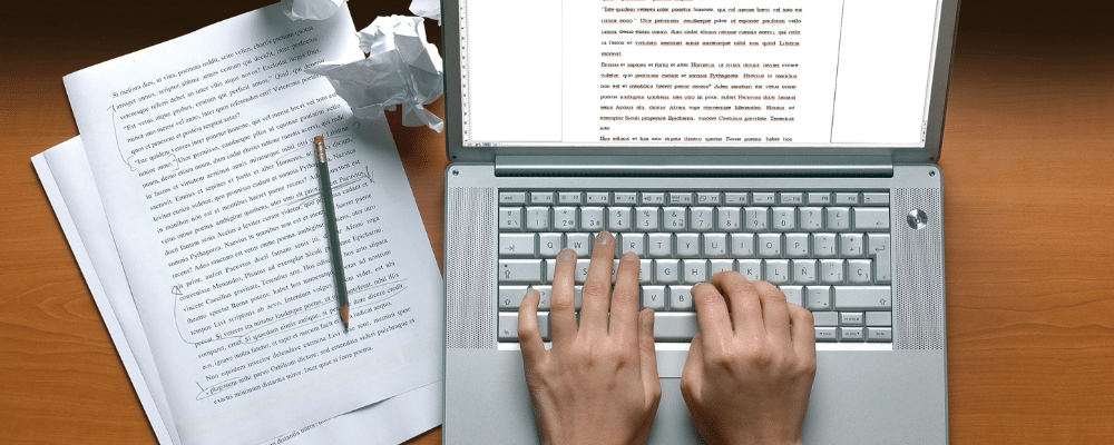 create compelling content on laptop with paper beside
